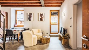 Un salon moderne avec un plafond en bois, un coin repas comprenant une table et des chaises, et un téléviseur posé sur un meuble en bois.