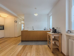 Eine moderne Küche mit Holzschränken, einer integrierten Spüle und einem kleinen Holztisch mit Wasserkocher.