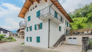 A multi-story building with a white facade, green shutters, and wooden balconies.