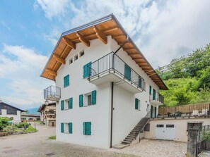 Ein mehrgeschossiges Gebäude mit weißer Fassade, grünen Fensterläden und hölzernen Balkonen.