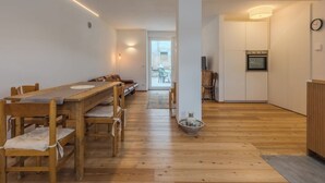 A modern kitchen with wooden cabinets, a built-in oven, and a dining area with a long wooden table and chairs.