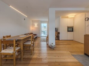 Eine moderne Küche mit Holzschränken, einem eingebauten Backofen und einem Essbereich mit einem langen Holztisch und Stühlen.