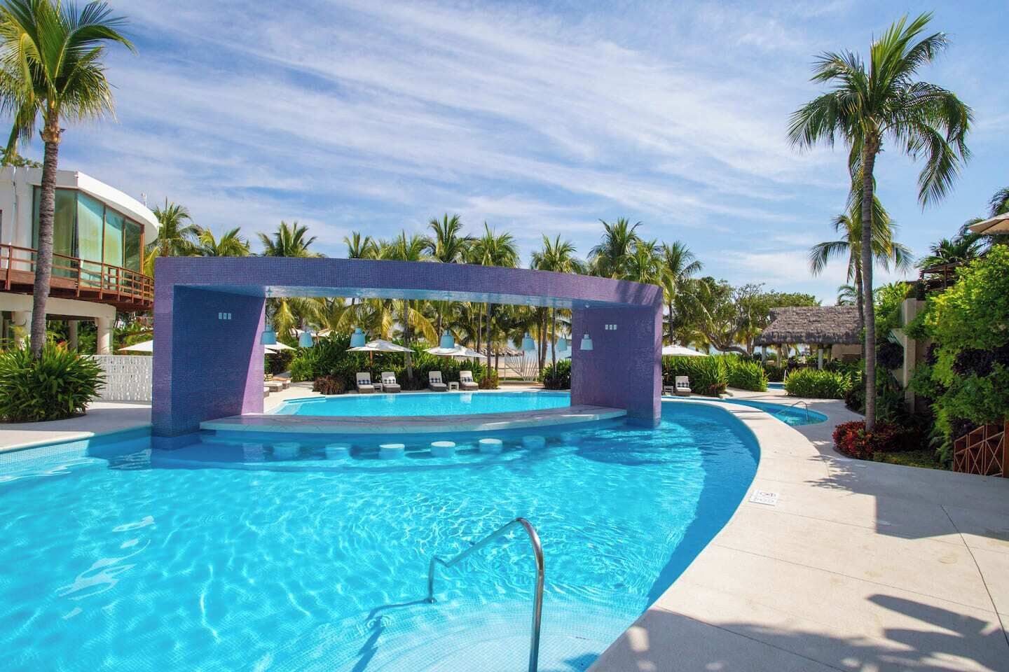 A swimming pool with a purple archway, surrounded by palm trees and lounge chairs.