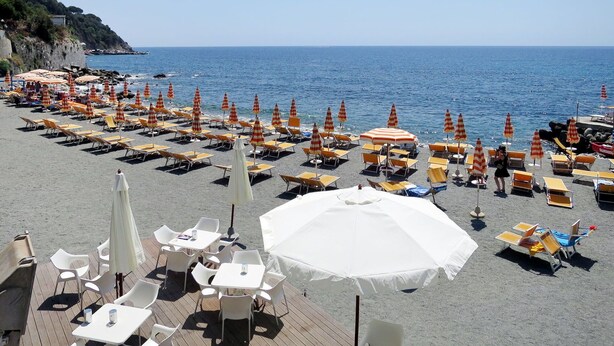 Ein Restaurant am Strand mit Außenbereich, inklusive Tischen, Stühlen und Sonnenschirmen.