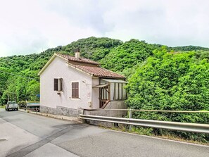 Una piccola casa a un piano con tetto spiovente, un camino in vista e un piccolo portico.