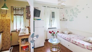 Ein kompakter Wohnbereich mit Küchenzeile, Essplatz, einer Sitzecke inklusive Sofa und einem kleinen Tisch mit Ventilator.