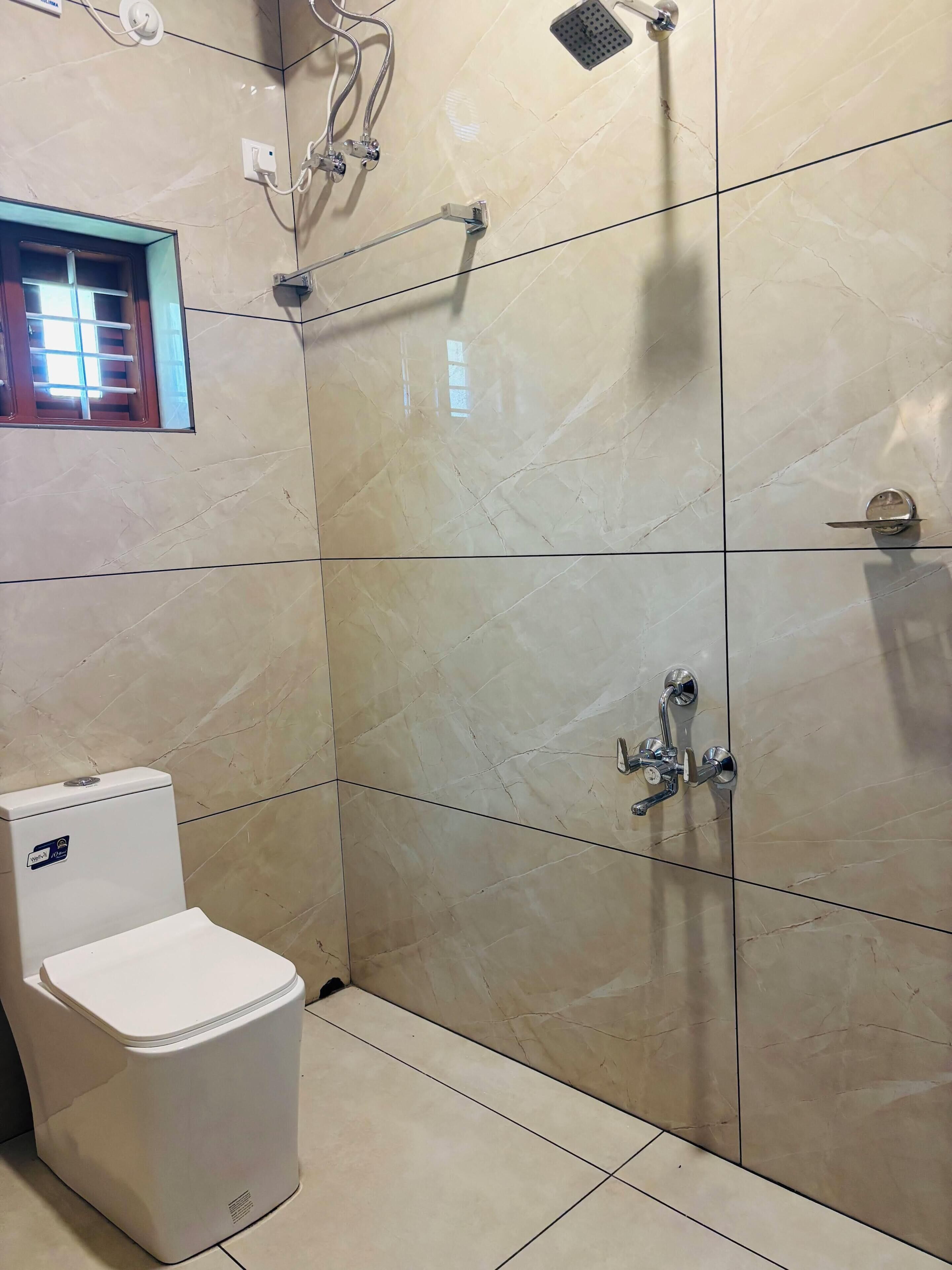 A bathroom with a toilet, a shower, and a window.