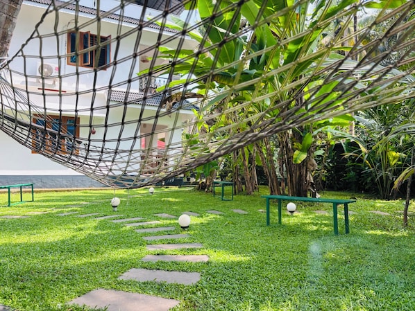 A hammock, stone steps, and a grassy area with benches. - Villa Lemon Garden (Varkala)