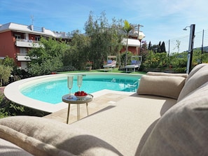 Une piscine avec des chaises longues et une table sur laquelle se trouvent des verres et des fraises.