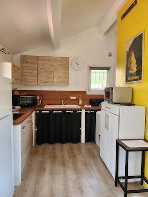 Eine kompakte Küche mit Holzausstattung, einer Mikrowelle, einem Spülbecken und einem kleinen Kühlschrank.