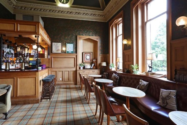 A bar area with stools, a bar counter, and a seating area with a bench and round tables.