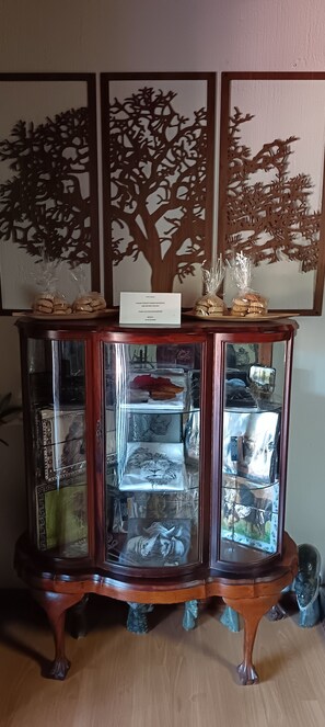Une vitrine en bois avec des portes en verre, contenant divers objets et une pancarte indiquant les articles en vente.