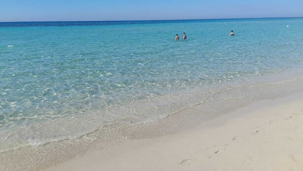 Una spiaggia con acque cristalline e una battigia sabbiosa.