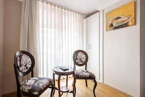 A room with two chairs, a small table, a painting on the wall, and a window with curtains. - My Way Teras Hotel (Adalar)