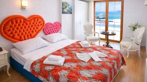 A hotel room with a large bed, heart-shaped headboards, a view of the sea, and a small table with chairs. - My Way Teras Hotel (Adalar)