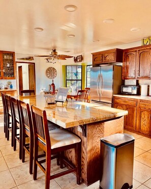 A kitchen with a central island, wooden cabinets, a refrigerator, and a microwave. - FarmStay HillTop wine country views 4BR/4BA (Paso Robles)