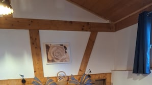 Et værelse med to senge, trægavle, trægulv, et lille træbord og en vægmonteret lampe.