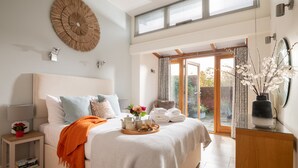 A bedroom with a bed, bedside table, and a view of the outdoors.