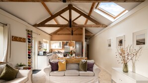 A spacious living area with a high ceiling, a sofa, a dining table, and a kitchen in the background.