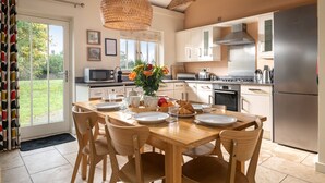 A modern kitchen with a dining area, large windows, and a view of the outdoors.