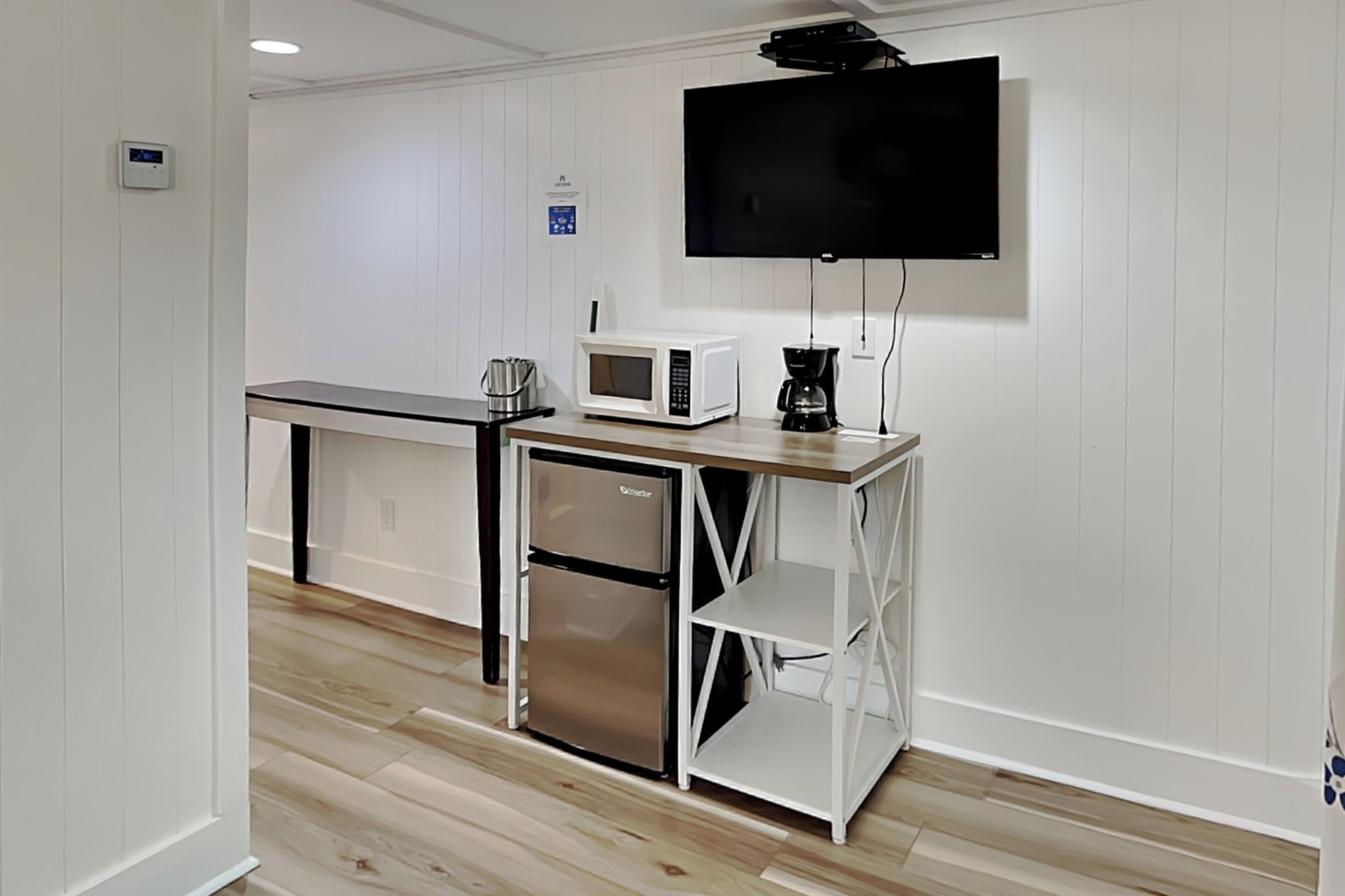 Una kitchenette equipada con microondas, cafetera y refrigerador.