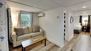 Ein Zimmer mit einer Couch, einem Couchtisch, einem Bett und einem kleinen Tisch mit einer Lampe.