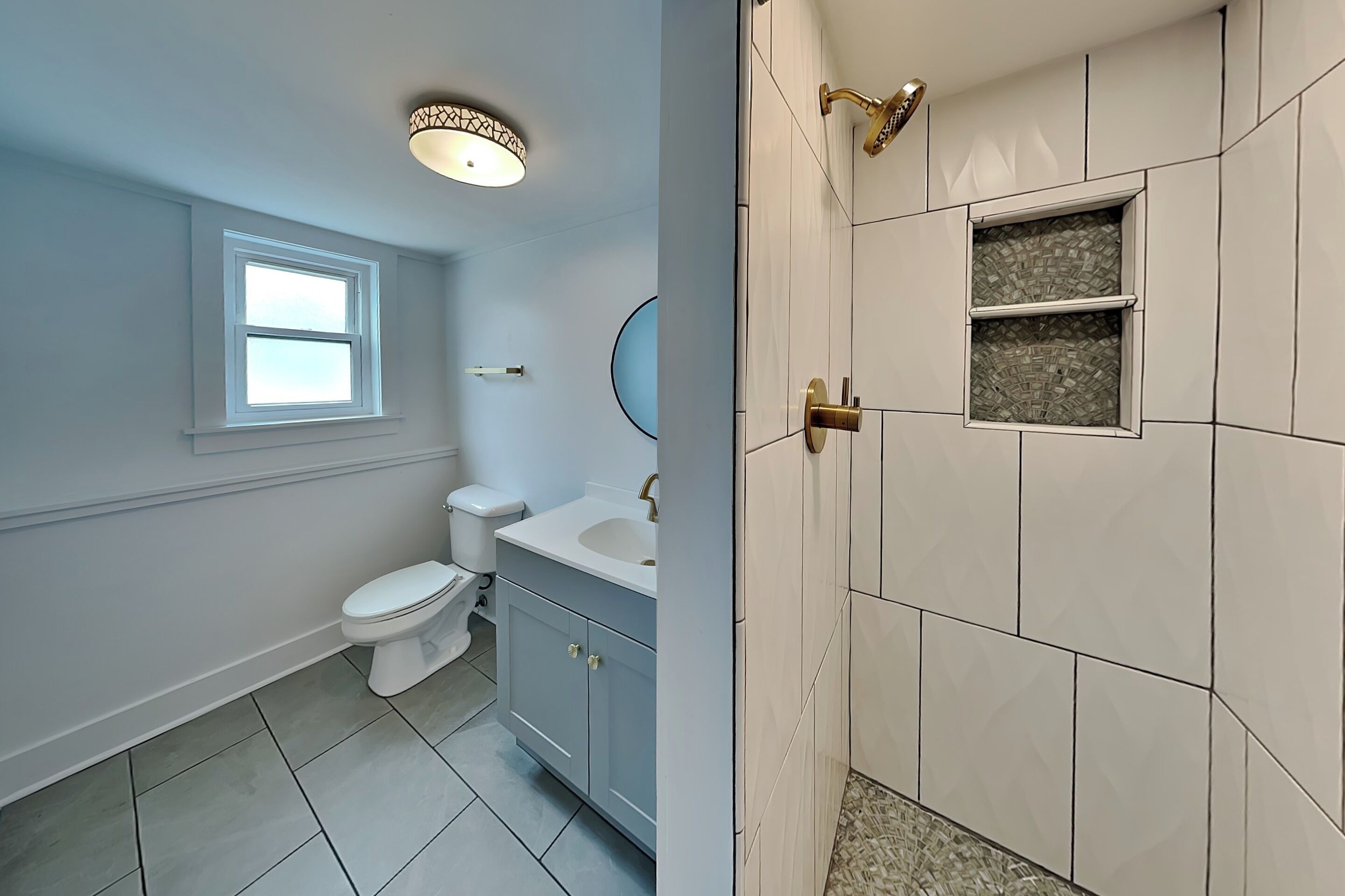 A bathroom with a toilet, sink, and shower area.