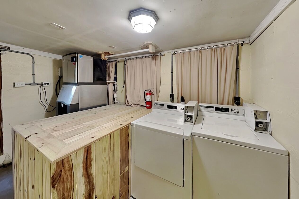 A compact kitchen with a wooden countertop, a washing machine, and a small refrigerator.
