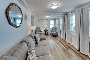 Ein modernes Hotelzimmer mit einer Couch, zwei Sesseln, einem kleinen Tisch und einem Spiegel.