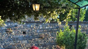 An outdoor dining area with stone walls, a pergola, and a view of a stone amphitheater. - An authentic corner of Tuscany. Relaxation, good food, close to Florence, Siena, Pisa (Toscana)