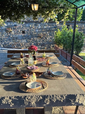 An outdoor dining area with stone walls, a pergola, and a view of a stone amphitheater. - An authentic corner of Tuscany. Relaxation, good food, close to Florence, Siena, Pisa (Toscana)