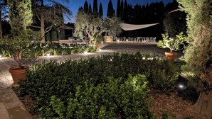 A well-lit outdoor area with a seating arrangement, surrounded by various plants and trees. - An authentic corner of Tuscany. Relaxation, good food, close to Florence, Siena, Pisa (Toscana)