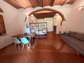A spacious living area with a dining table, chairs, a sofa, and a fireplace.