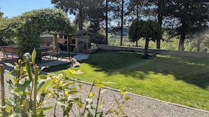 A well-maintained garden with a patio area, a stone wall, and a small building with a chimney.