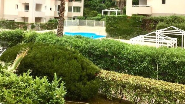 Ein Wohngebäude mit Schwimmbad, umgeben von üppiger Vegetation und Palmen.