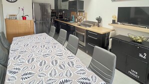 Une cuisine moderne avec un coin repas, une chambre à coucher aménagée en mezzanine et un salon équipé d’un téléviseur.