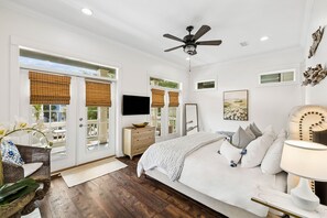 Une chambre à coucher avec un lit, une table de chevet, une lampe et un ventilateur de plafond.