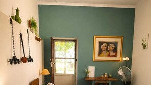A bedroom with a bed, bedside tables, a desk, a chair, a fan, a door, and a wall with a framed picture. - Amazing 2-bedroom cottage in Graafwater, perfect for a relaxing getaway (Graafwater)