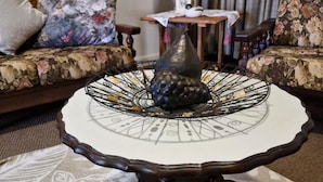 A round table with a decorative metal centerpiece, a sofa with floral upholstery, and a lamp in the background. - Amazing 2-bedroom cottage in Graafwater, perfect for a relaxing getaway (Graafwater)