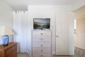 Habitación con televisión en una cómoda, una lámpara, una puerta y vistas al exterior.