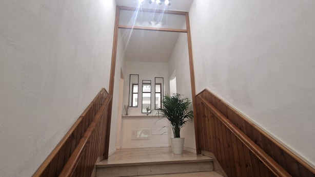 A staircase with wooden railings leading to a landing with a potted plant and framed pictures. - Casa di Riccardo Apartment in the living heart of Tuscany between Florence and Pisa (San Miniato)