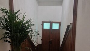 A hallway with wooden flooring, a potted plant, and a staircase leading to a door with frosted glass panels. - Casa di Riccardo Apartment in the living heart of Tuscany between Florence and Pisa (San Miniato)