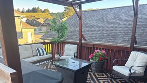 En overdækket terrasse med sofa, stole, et bord og en potteplante.