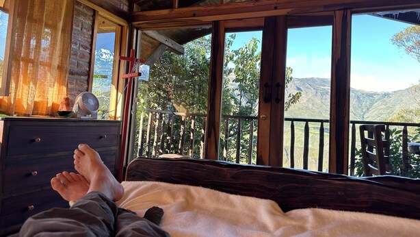A wooden cabin with a bed, a dresser, and a view of mountains. - La Casita Cabin: Beautiful 1-bedroom cabin in Cahuasquí for a relaxing stay (Calle Bolivar)