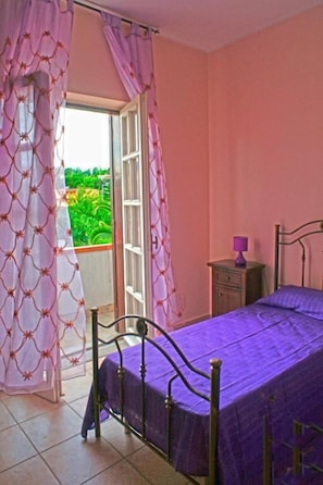 A room with a bed, a nightstand, and a window with curtains. - LA CASA DI MIR0' (Catanzaro)