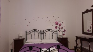 Un dormitorio con una cama, dos mesitas de noche, un tocador y un espejo.