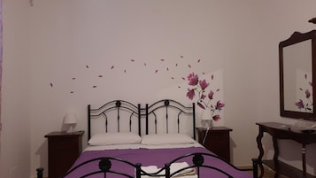 Un dormitorio con una cama, dos mesitas de noche, un tocador y un espejo.