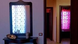 Un pasillo con una consola de madera oscura, un espejo y una puerta que da a otra habitación.