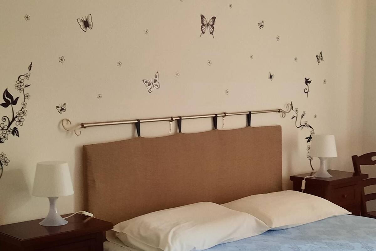 A bedroom with a bed, two bedside tables, a headboard, and wall decorations.