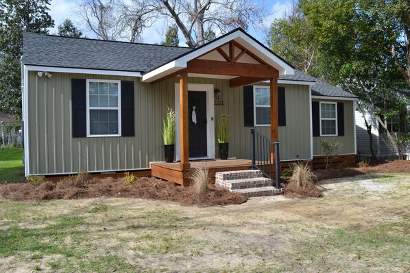 A single-story house with a front porch, a door, and a small front yard.